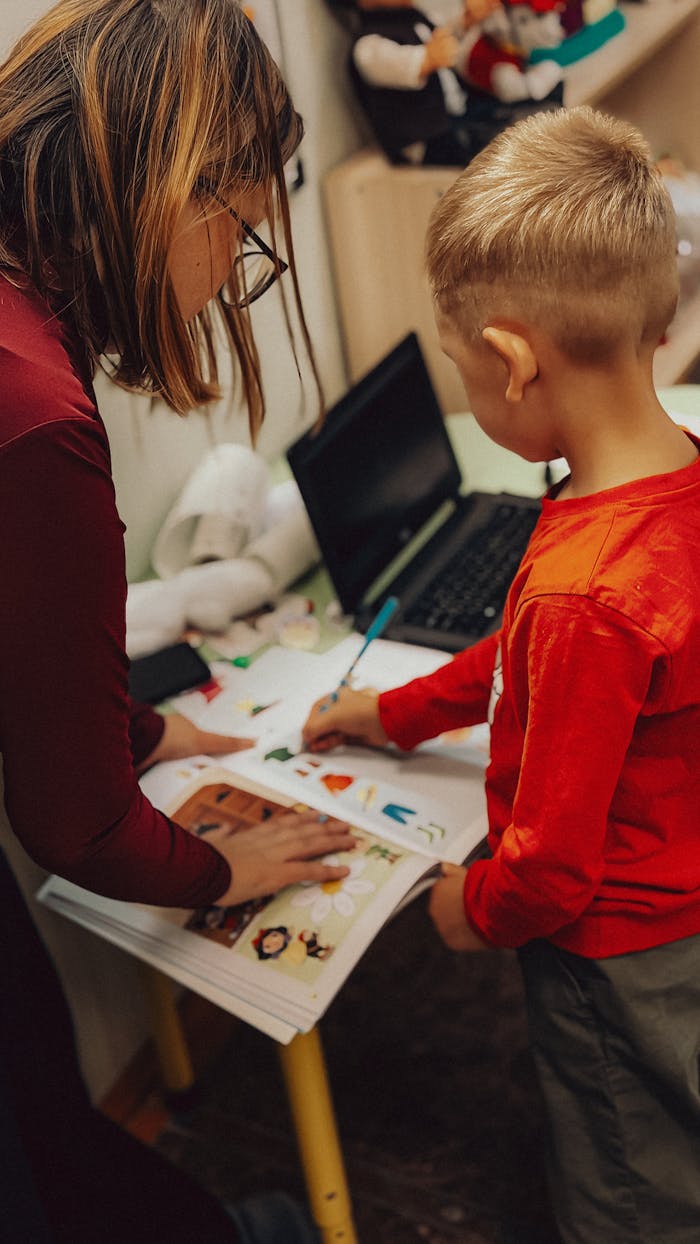 Teacher assisting a child with educational activities in a learning environment.